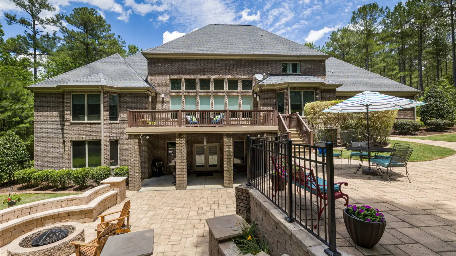 A brick home behind a paver patio with seat walls and a fire pit